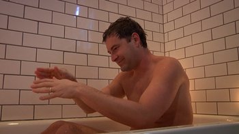 Movie still from “Creep” (2014), directed by Patrick Brice – A man sitting in a bath tub in a bathroom; Medium shot, Low angle