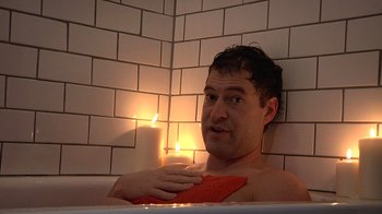 Movie still from “Creep” (2014), directed by Patrick Brice – A man sitting in a bath tub next to a lit candle; Close Up shot, High angle
