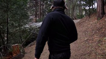 Movie still from “Creep” (2014), directed by Patrick Brice – A man walking on a trail in the woods; Medium shot, Over the shoulder angle