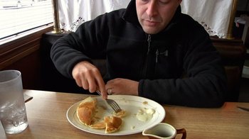 Movie still from “Creep” (2014), directed by Patrick Brice – A man sitting at a table eating a piece of cake; Close Up shot, High angle