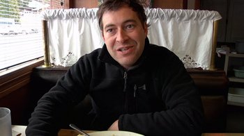 Movie still from “Creep” (2014), directed by Patrick Brice – A person sitting at a table with a plate of food; Close Up shot, Low angle