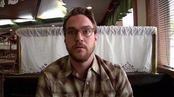 Movie still from “Creep” (2014), directed by Patrick Brice – A person wearing glasses and a plaid shirt; Close Up shot, High angle