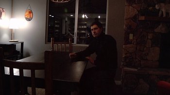 Movie still from “Creep” (2014), directed by Patrick Brice – A man sitting at a table in front of a window; Medium shot, Low angle