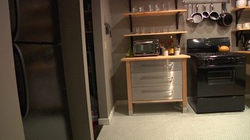 Movie still from “Creep” (2014), directed by Patrick Brice – A kitchen area with a microwave and a shelf; Wide shot, High angle