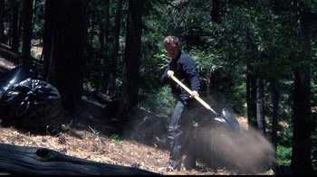 Movie still from “Creep” (2014), directed by Patrick Brice – A man with a shovel in the woods; Wide shot, High angle