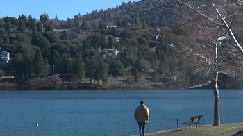 Movie still from “Creep” (2014), directed by Patrick Brice – A man standing on the edge of a lake looking out at the trees; Extreme Wide shot, Low angle