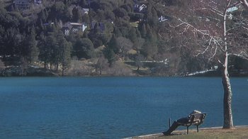 Movie still from “Creep” (2014), directed by Patrick Brice – A bench near a body of water with a house in the background; Extreme Wide shot, High angle