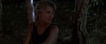 A woman in a black shirt is sitting in the dark