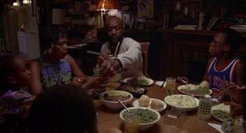 Movie still from “Crooklyn” (1994), directed by Spike Lee – A man and two children sitting at a dinner table; Medium shot, High angle