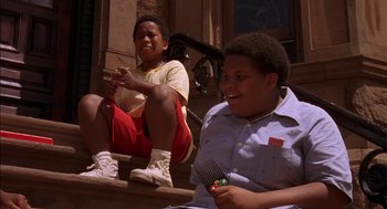 Movie still from “Crooklyn” (1994), directed by Spike Lee – Two young boys sitting on steps and one is holding a comb; Medium shot, Low angle