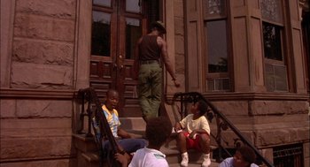 Movie still from “Crooklyn” (1994), directed by Spike Lee – A group of young people sitting on the steps of a building; Wide shot, Low angle