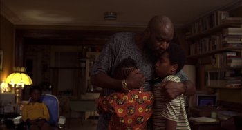 Movie still from “Crooklyn” (1994), directed by Spike Lee – A man and two children are hugging in a living room; Medium shot, Low angle