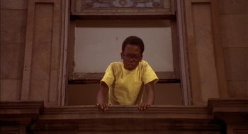 Movie still from “Crooklyn” (1994), directed by Spike Lee – A boy in a yellow shirt is standing at the top of the stairs; Medium shot, Low angle