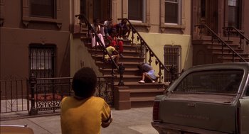 Movie still from “Crooklyn” (1994), directed by Spike Lee – A group of people sitting on steps in front of a building; Wide shot, High angle