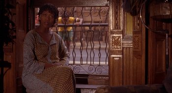 Movie still from “Crooklyn” (1994), directed by Spike Lee – A woman sitting on a chair in front of a window; Medium shot, Over the shoulder angle