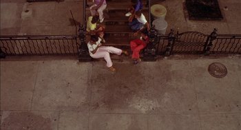 Movie still from “Crooklyn” (1994), directed by Spike Lee – A group of people sitting on a set of stairs; Extreme Wide shot, Overhead angle