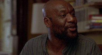 Movie still from “Crooklyn” (1994), directed by Spike Lee – A man with a beard is sitting in a room; Close Up shot, Low angle