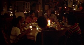 Movie still from “Crooklyn” (1994), directed by Spike Lee – A group of people sitting around a table with candles; Wide shot, High angle