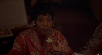 Movie still from “Crooklyn” (1994), directed by Spike Lee – A woman sitting at a table eating a piece of food; Close Up shot, Over the shoulder angle