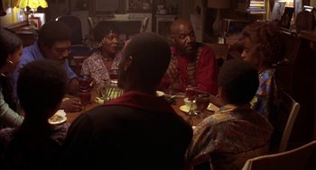 Movie still from “Crooklyn” (1994), directed by Spike Lee – A group of people sitting around a table; Medium shot, High angle