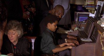 Movie still from “Crooklyn” (1994), directed by Spike Lee – A man and a boy using a computer at a party; Medium shot, High angle