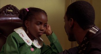 Movie still from “Crooklyn” (1994), directed by Spike Lee – A little girl looking at a man with his hand to her ear; Close Up shot, Over the shoulder angle