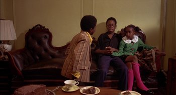 Movie still from “Crooklyn” (1994), directed by Spike Lee – A group of people sitting on top of a brown couch; Medium shot, Over the shoulder angle