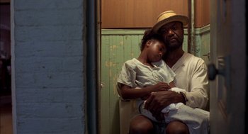 Movie still from “Crooklyn” (1994), directed by Spike Lee – An older man holding a little girl in his arms; Medium shot, High angle