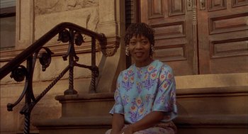 Movie still from “Crooklyn” (1994), directed by Spike Lee – A woman sitting on a step in front of a building; Medium shot, Low angle