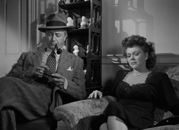Movie still from “Crossfire” (1947), directed by Edward Dmytryk – A man and a woman sitting on a couch; Medium shot, High angle