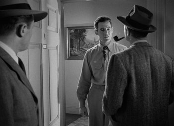 Movie still from “Crossfire” (1947), directed by Edward Dmytryk – A man in a suit and tie standing next to two other men; Medium shot, Over the shoulder angle