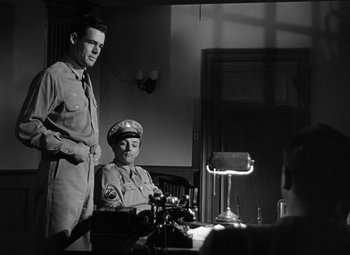 Movie still from “Crossfire” (1947), directed by Edward Dmytryk – Two men in uniform standing in front of a table; Medium shot, Over the shoulder angle