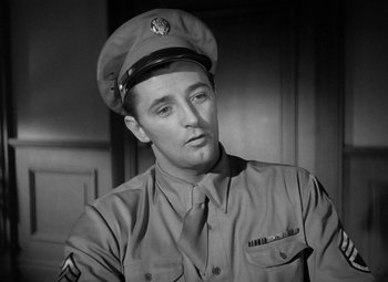 Movie still from “Crossfire” (1947), directed by Edward Dmytryk – A man in a military uniform wearing a hat and neck tie; Close Up shot, Low angle
