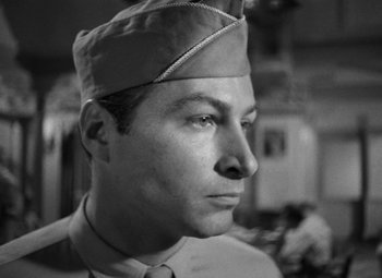 Movie still from “Crossfire” (1947), directed by Edward Dmytryk – A black and white photo of a man wearing a hat; Close Up shot, Low angle