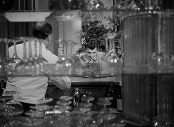 Movie still from “Crossfire” (1947), directed by Edward Dmytryk – A man sitting in front of a mirror in a restaurant; Medium shot, Over the shoulder angle
