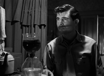 Movie still from “Crossfire” (1947), directed by Edward Dmytryk – A black and white photo of a man sitting at a table; Medium shot, Over the shoulder angle