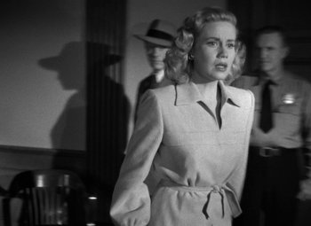 Movie still from “Crossfire” (1947), directed by Edward Dmytryk – A black and white photo of a woman in a dress; Medium shot, Low angle