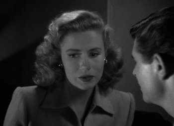 Movie still from “Crossfire” (1947), directed by Edward Dmytryk – An old photo of a woman talking to another woman; Close Up shot, Over the shoulder angle
