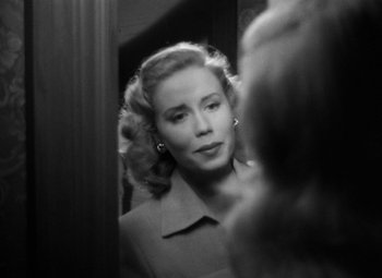 Movie still from “Crossfire” (1947), directed by Edward Dmytryk – A black and white photo of a woman looking in a mirror; Close Up shot, Over the shoulder angle