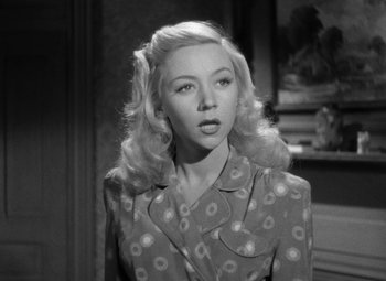 Movie still from “Crossfire” (1947), directed by Edward Dmytryk – A black and white photo of a woman in a polka dot suit; Close Up shot, High angle