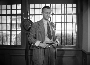 Movie still from “Crossfire” (1947), directed by Edward Dmytryk – A black and white photo of a man in a suit and tie; Medium shot, Low angle