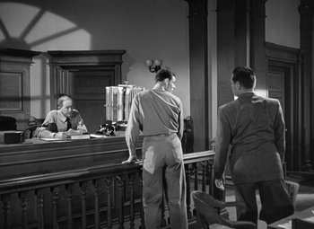 Movie still from “Crossfire” (1947), directed by Edward Dmytryk – A man standing in front of a judge in a courtroom; Medium shot, Low angle
