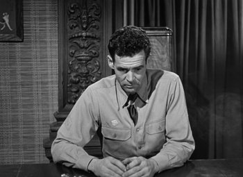 Movie still from “Crossfire” (1947), directed by Edward Dmytryk – A black and white photo of a man sitting at a table; Medium shot, High angle