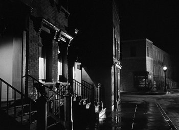 Movie still from “Crossfire” (1947), directed by Edward Dmytryk – A black - and - white photo of a city street at night; Extreme Wide shot, High angle