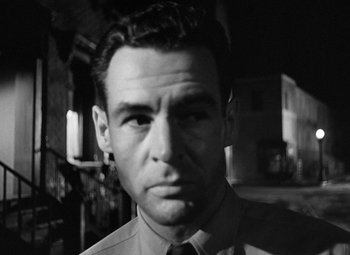 Movie still from “Crossfire” (1947), directed by Edward Dmytryk – Black and white photograph of a man in a shirt and tie; Close Up shot, Low angle