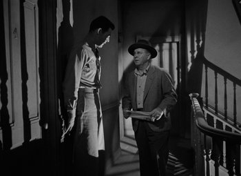 Movie still from “Crossfire” (1947), directed by Edward Dmytryk – A man in a hat is talking to another man in a hat; Medium shot, Over the shoulder angle