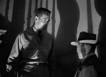 Movie still from “Crossfire” (1947), directed by Edward Dmytryk – A man in a suit and tie standing next to another man in a hat; Medium shot, Low angle