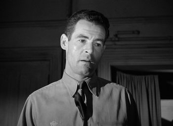 Movie still from “Crossfire” (1947), directed by Edward Dmytryk – Black and white photograph of a man smoking a cigarette; Close Up shot, Low angle