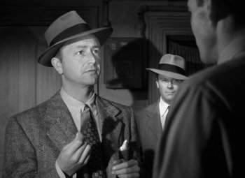 Movie still from “Crossfire” (1947), directed by Edward Dmytryk – A man in a suit and hat talking to another man; Close Up shot, Low angle