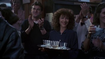 Movie still from “Crossing Delancey” (1988), directed by Joan Micklin Silver – A woman holding a tray of drinks in front of a crowd; Medium shot, Over the shoulder angle